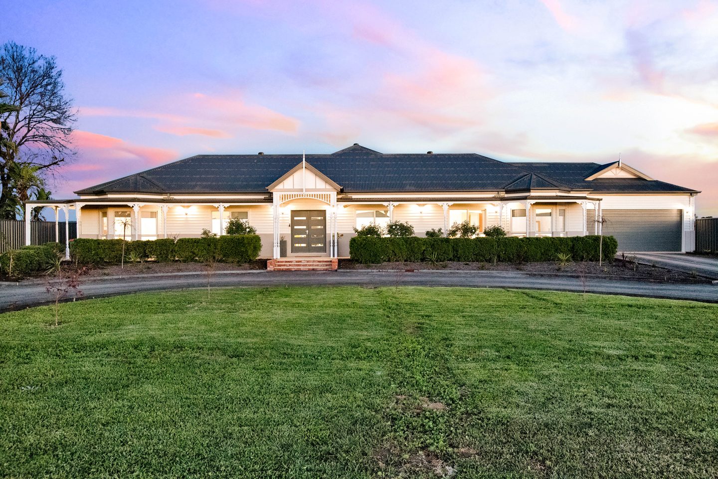 The long front verandah, gabled entrance and curved driveway at dusk
