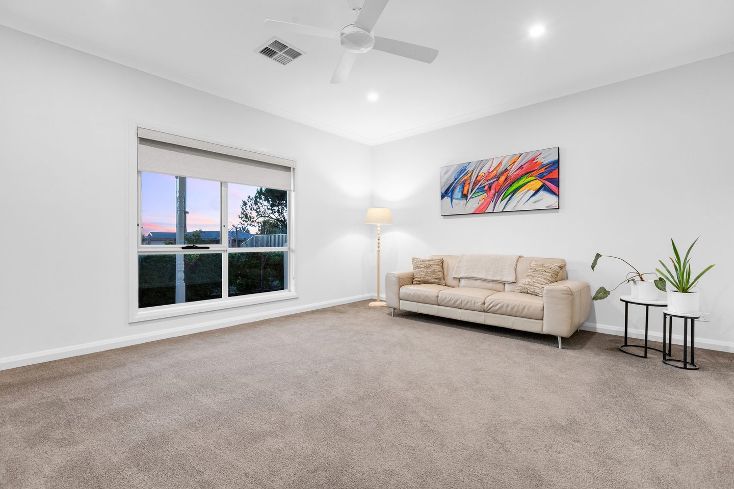 Carpeted living room with a broad window and ceiling fan