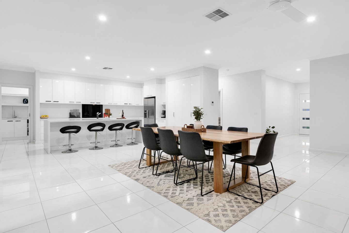 Open kitchen and dining area with white cabinetry, an island bench and tiled floors