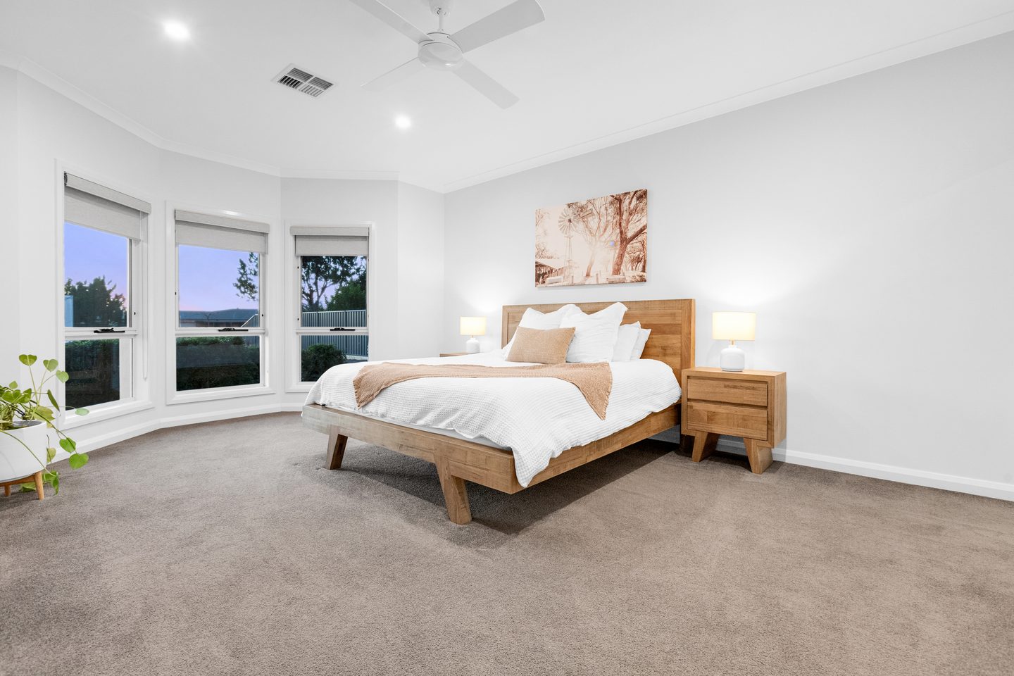 Main bedroom with bay windows, carpet and a ceiling fan