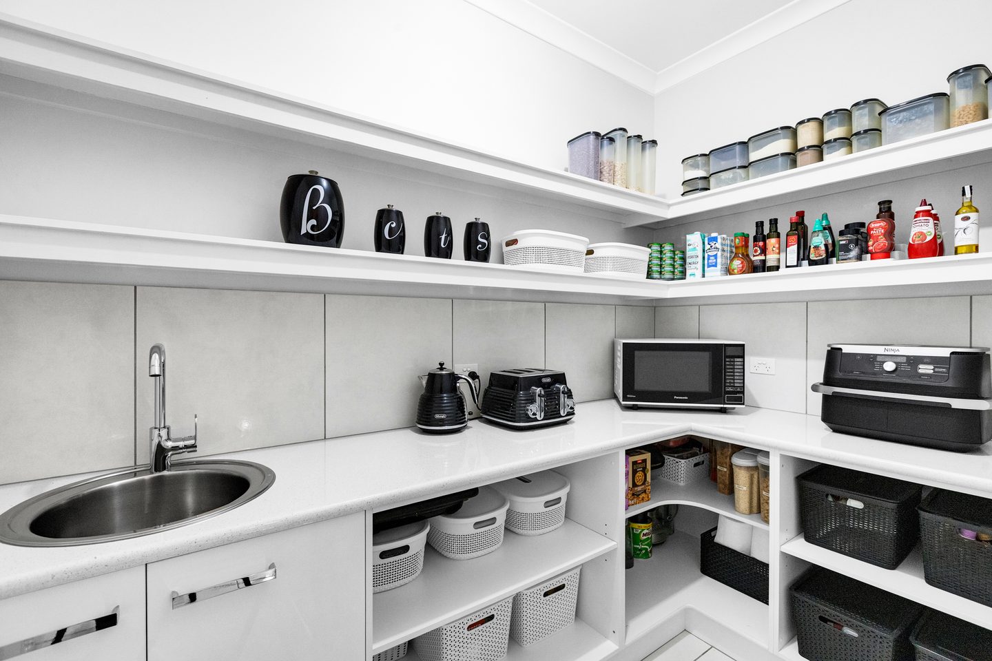 Walk-in pantry with open shelves, a bench and a sink