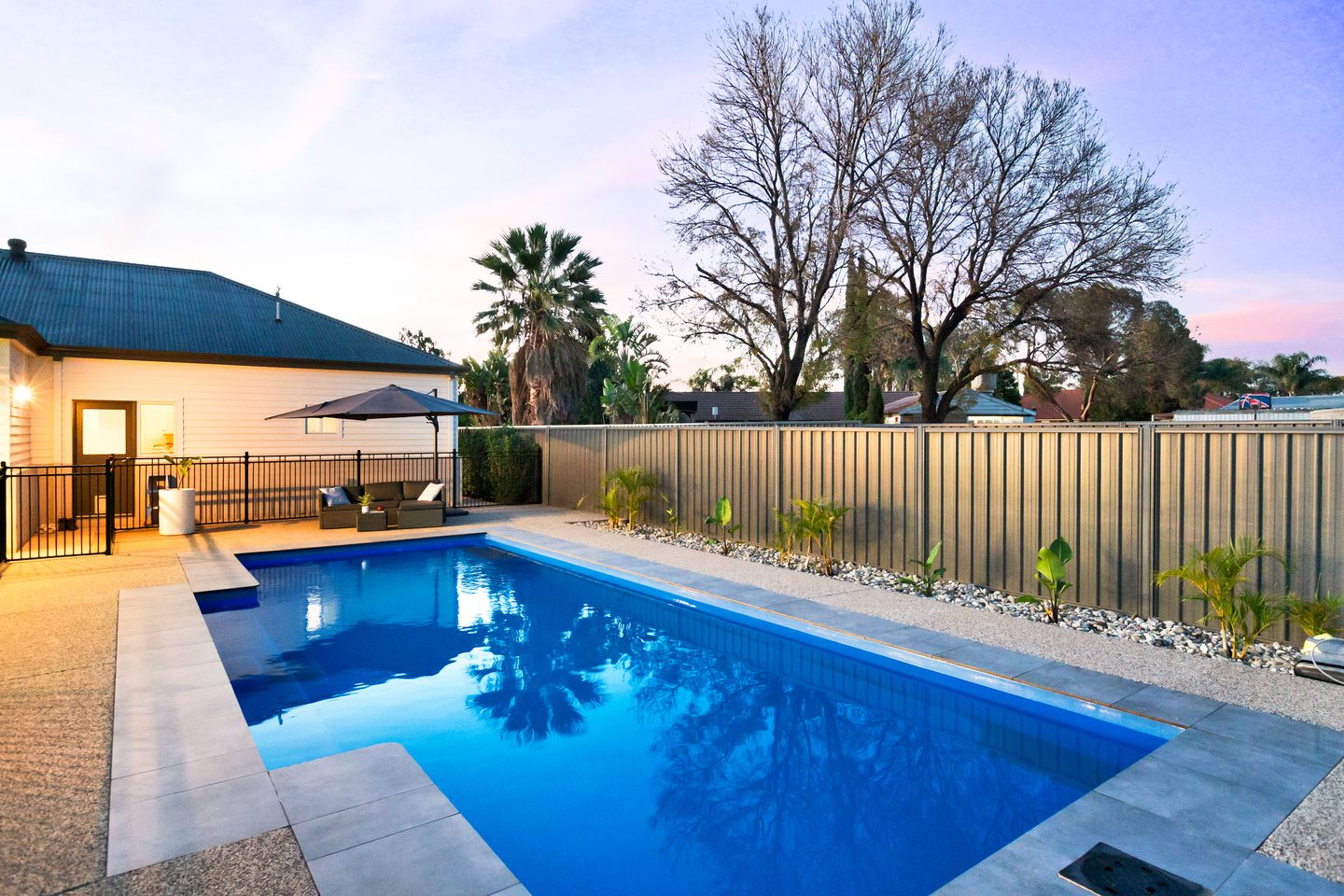 In-ground pool with paved surrounds beside the home